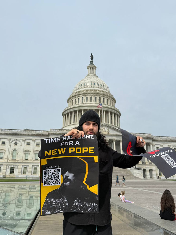 un croyant tient une affiche indiquant qu’Abdullah Hashem est le nouveau pape