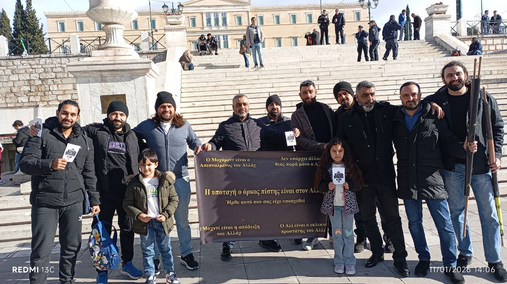 مؤمنون من دين السلام والنور الأحمدي يسيرون في أثينا، يلوّحون بفخر برايتهم السوداء رمزِ البيعة لله، ويعلنون دعوة المهدي للعالم.