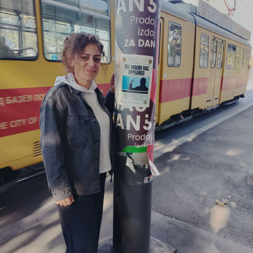 a refugee spreads flyers of Aba Al-Sadiq in Serbia