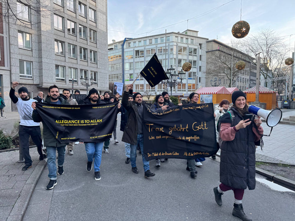 Unité à Essen ! Répandre le message de « L’humanité d’abord » et que la religion est une personne. Défiler bras dessus bras dessous sous la bannière « L’allégeance est à Dieu ».