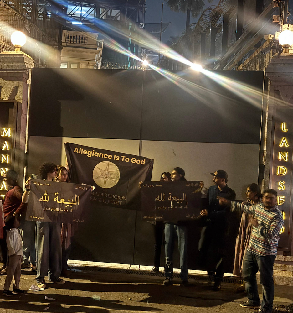 Onze croyants de l’AROPL se tiennent unis devant Mannat, la maison de SRK, bannières levées portant « L’allégeance est à Dieu », incarnant l’harmonie interreligieuse dans les rues animées de Mumbai.