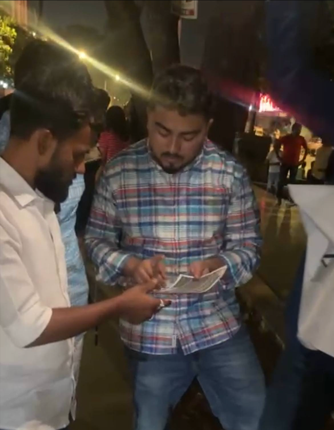 Des gens, près des vendeurs de Mannat, écoutent attentivement les croyants expliquer la mission du Qaim pour les pauvres.