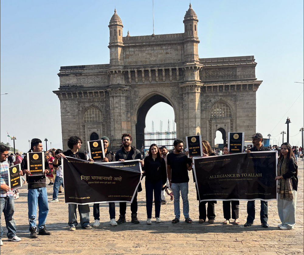 Des membres de la Religion Ahmadie de la Paix et de la Lumière tiennent des bannières promouvant l’unité entre les religions à la Porte de l’Inde, à Mumbai, le 15 décembre 2025.