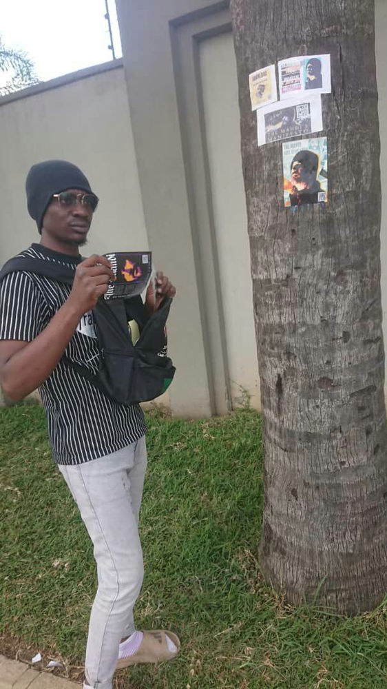 Zambian follower of Aba Al-Sadiq next to a flyer