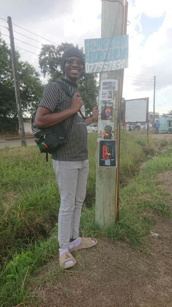 Zambian follower of Aba Al-Sadiq next to a flyer