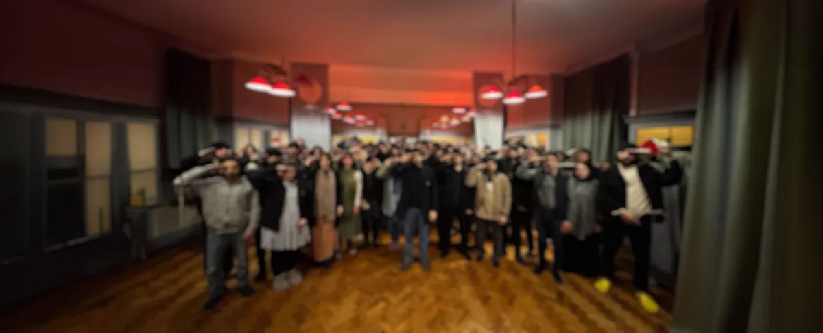 Un groupe nombreux de croyants, debout dans une salle, faisant le salut.